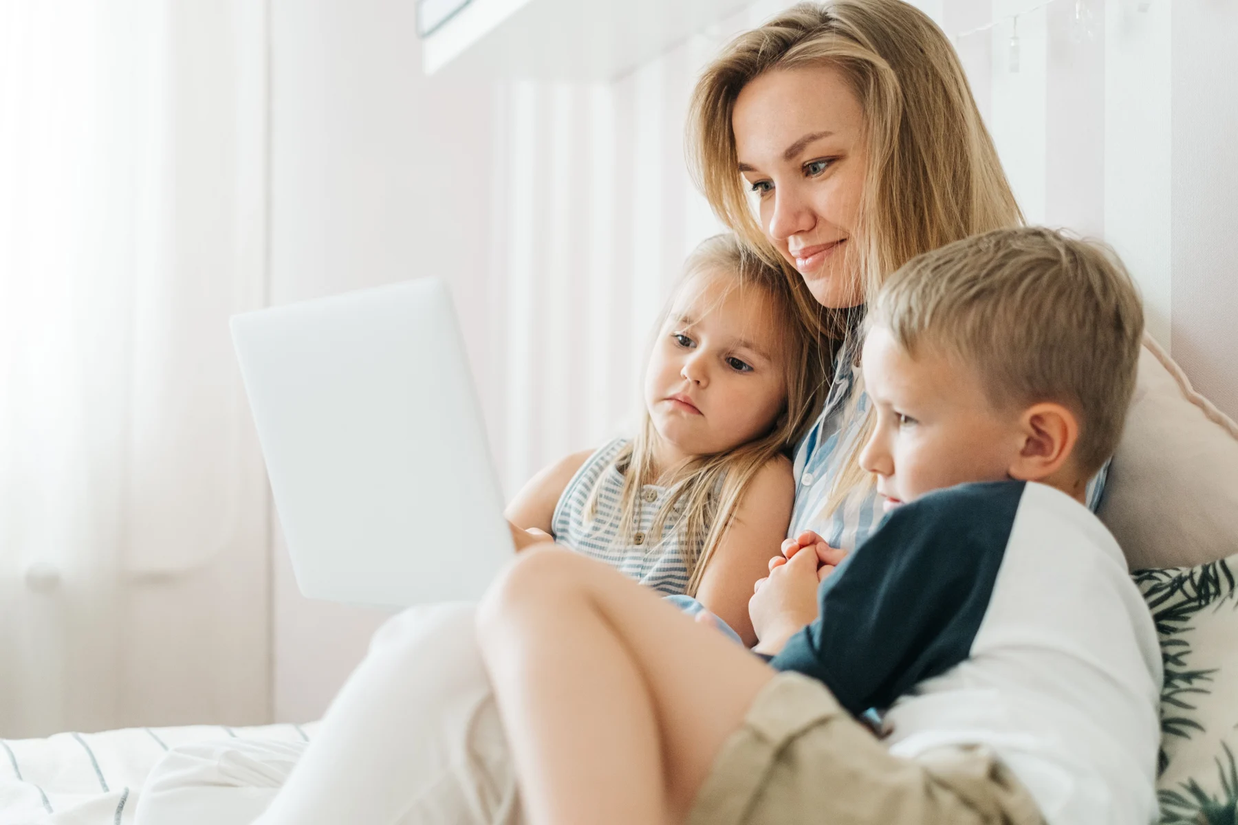 A mother and her two children exploring a laptop together